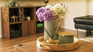 Ein Holztisch mit Blumen in einer Vase, einer Kerze und einem Tablett.