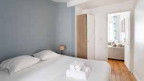 Una camera d'albergo moderna con un letto grande, un armadio in legno e vista su un soggiorno con divano.