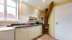 A kitchen with a built-in washing machine, wooden beams, and a wine rack.