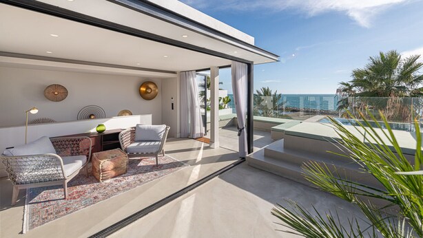 Un espacio exterior moderno con una zona de estar, una pequeña mesa y vistas al océano.