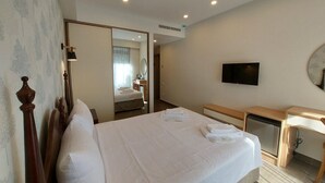 Una habitación de hotel con cama, escritorio, televisor y espejo.