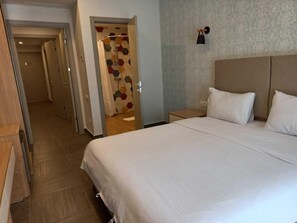 A hotel room with a large bed, a nightstand, a wall-mounted lamp, and a shower with a geometric tile design. - Avenue 30 Hotel (Yerevan)