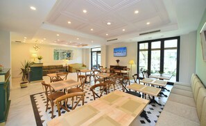 A hotel lobby with a central seating area, multiple tables, and chairs, a reception desk, and large windows providing a view of the outdoors. - Avenue 30 Hotel (Yerevan)