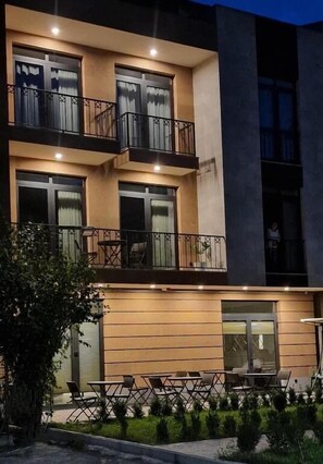 A multi-story building with balconies, outdoor seating, and a well-lit entrance. - Avenue 30 Hotel (Yerevan)
