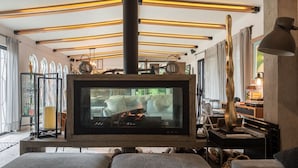 A cozy living room with a fireplace, a large flat-screen TV, and a modern ceiling design. - Tepoztlán Escape with Jacuzzi, Fireplace & Games (San Miguel Cañadas)