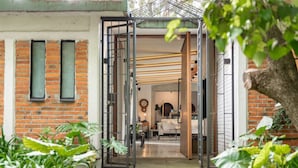 A doorway leading into a room with a brick wall, a window, and a plant in the foreground. - Tepoztlán Escape with Jacuzzi, Fireplace & Games (San Miguel Cañadas)