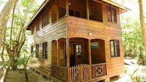 A wooden cabin with a balcony, surrounded by trees. - Take it easy at our eco friendly beach cabins where life meets nature .funfilled (Westmoreland)