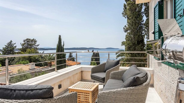 A balcony with wicker furniture, a grill, and a view of the sea. - Villa Garden Heights by MyWaycation (Hvar)