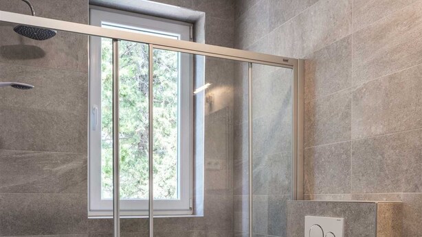 Ein modernes Badezimmer mit Glasdusche, Toilette und Waschbecken.