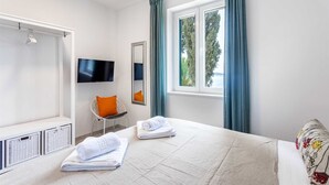 A bedroom with a bed, a TV, a window with curtains, a chair, and a mirror. - Villa Garden Heights by MyWaycation (Hvar)