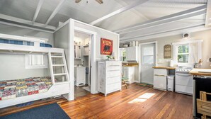 Un estudio compacto con una litera, kitchenette y un pequeño comedor.