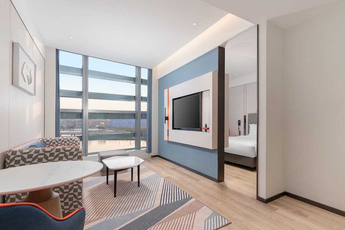 Ein modernes Hotelzimmer mit großem Fenster, Flachbildfernseher, Bett und Bad.