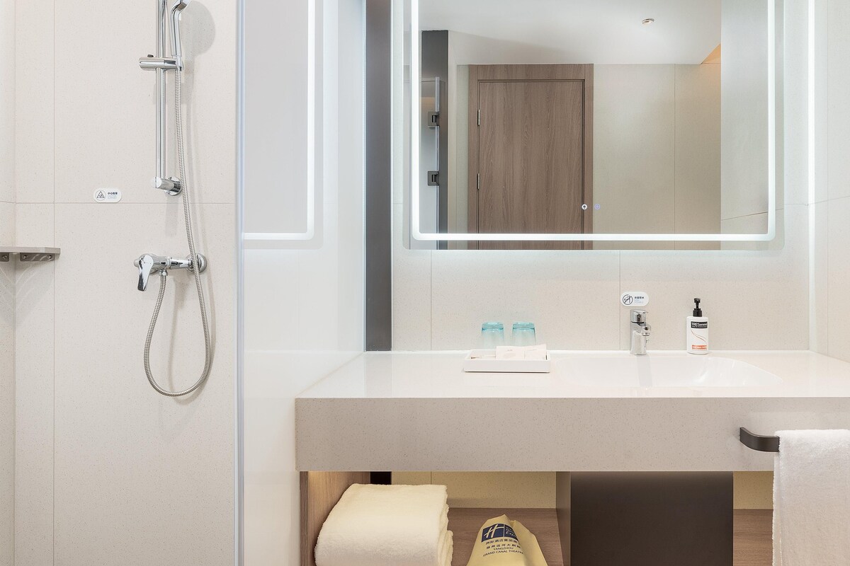 A modern bathroom with a shower, a sink, and a mirror.