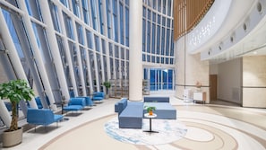 A spacious lobby with high ceilings, large windows, and modern seating areas.