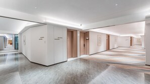 Un pasillo moderno de hotel con piso de mármol pulido, puertas de madera y decoración minimalista.
