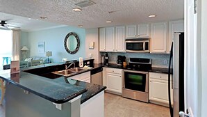 Una cocina moderna con armarios blancos, electrodomésticos de acero inoxidable y encimera de granito negro.