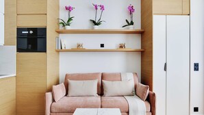 A modern living room with a sofa, a coffee table, and wooden shelving with decorative items.