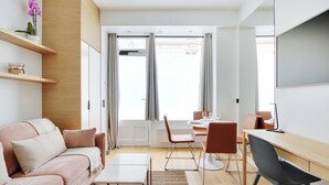 A modern living room with a sofa, coffee table, and dining area with chairs and a table.