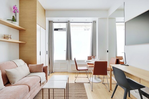 Ein modernes Wohnzimmer mit einer Couch, einem Couchtisch und einem Essbereich mit Stühlen und einem Tisch.