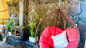 A stone wall, a hanging chair, and a fireplace. - Charming 3-bedroom cabin in with AC, spa, game room, firepit & EV charger  (Old Station)