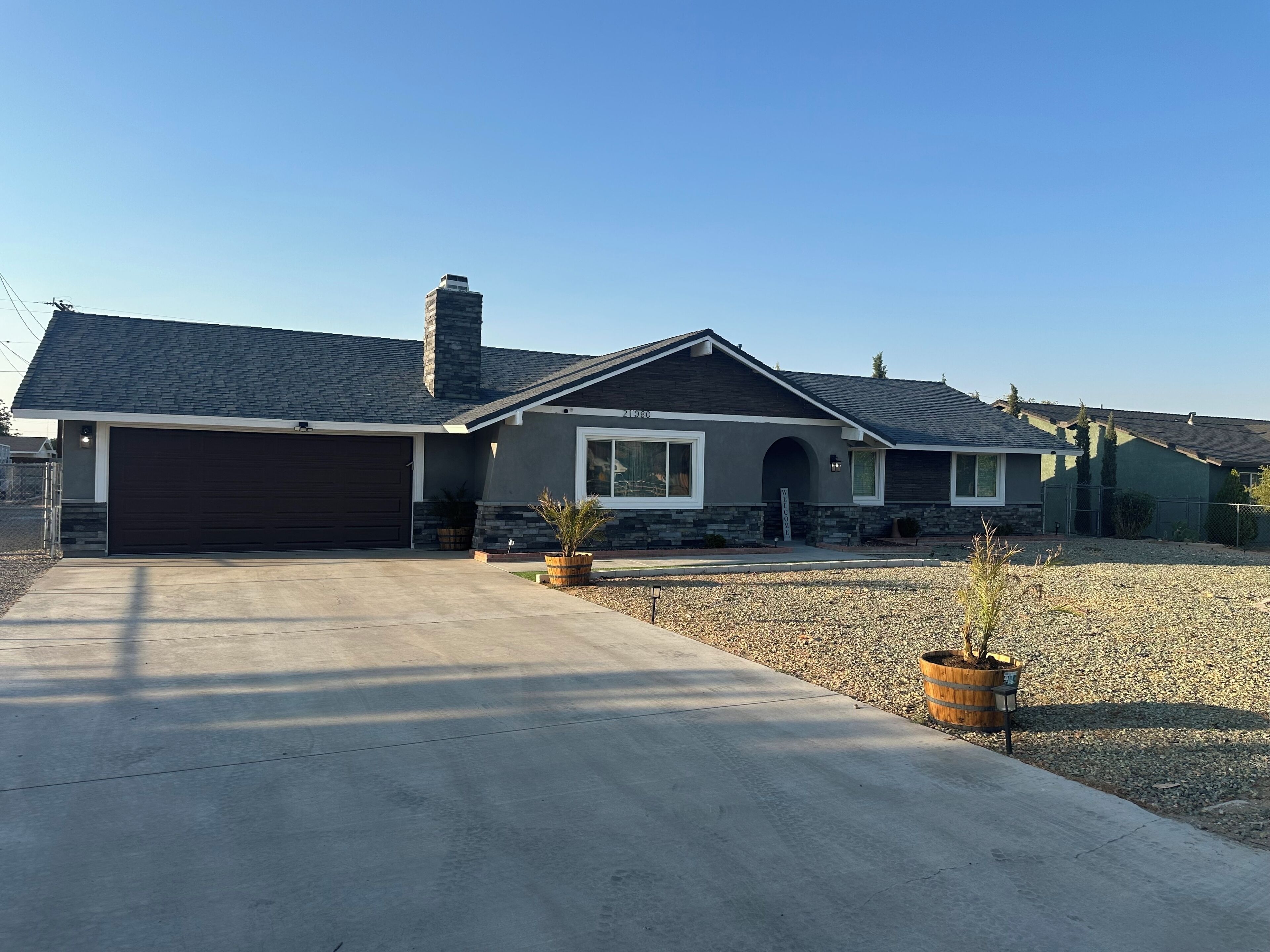 A single-story house with a dark garage door, a stone facade, and a sloped roof.
