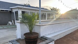 A modern building with a large windowed porch, a potted plant, and a concrete retaining wall. - 3-bdrm house in charming Apple Valley w/ WiFi, AC, encl'd patio, & large yard.  (Apple Valley)