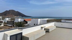 A rooftop terrace with a view of the sea and a mountain.