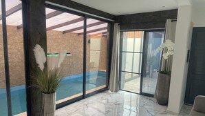 A spacious room with a large sliding glass door leading to an outdoor area, a marble-tiled floor, and a potted plant.