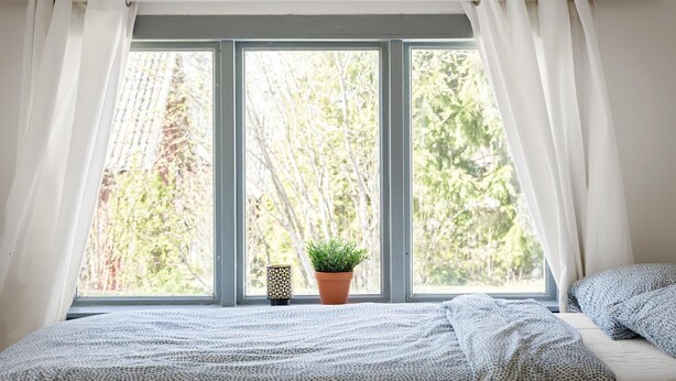A bedroom with a large window, a bed with a patterned blanket, a small potted plant, and a decorative candle holder. - OWN HOUSE, CLOSE TO WORK ESKILSTUNA STRÄNGNÄS, 1H STOCKHOLM, PARKING, WIFI, LAUNDRY (Södermanlands län)