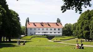 A large, white building with a red-tiled roof, surrounded by a well-maintained lawn and trees. - OWN HOUSE, CLOSE TO WORK ESKILSTUNA STRÄNGNÄS, 1H STOCKHOLM, PARKING, WIFI, LAUNDRY (Södermanlands län)