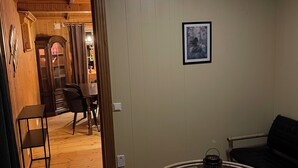 Una stanza con un tavolo rotondo, una sedia, un piccolo tavolo con una lanterna e un quadro appeso al muro.