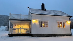 Un piccolo edificio bianco con un balcone e due finestre, immerso nella neve.