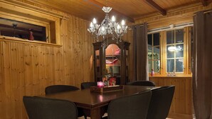 Una sala da pranzo con pannelli in legno, un lampadario, un tavolo in legno e quattro sedie.