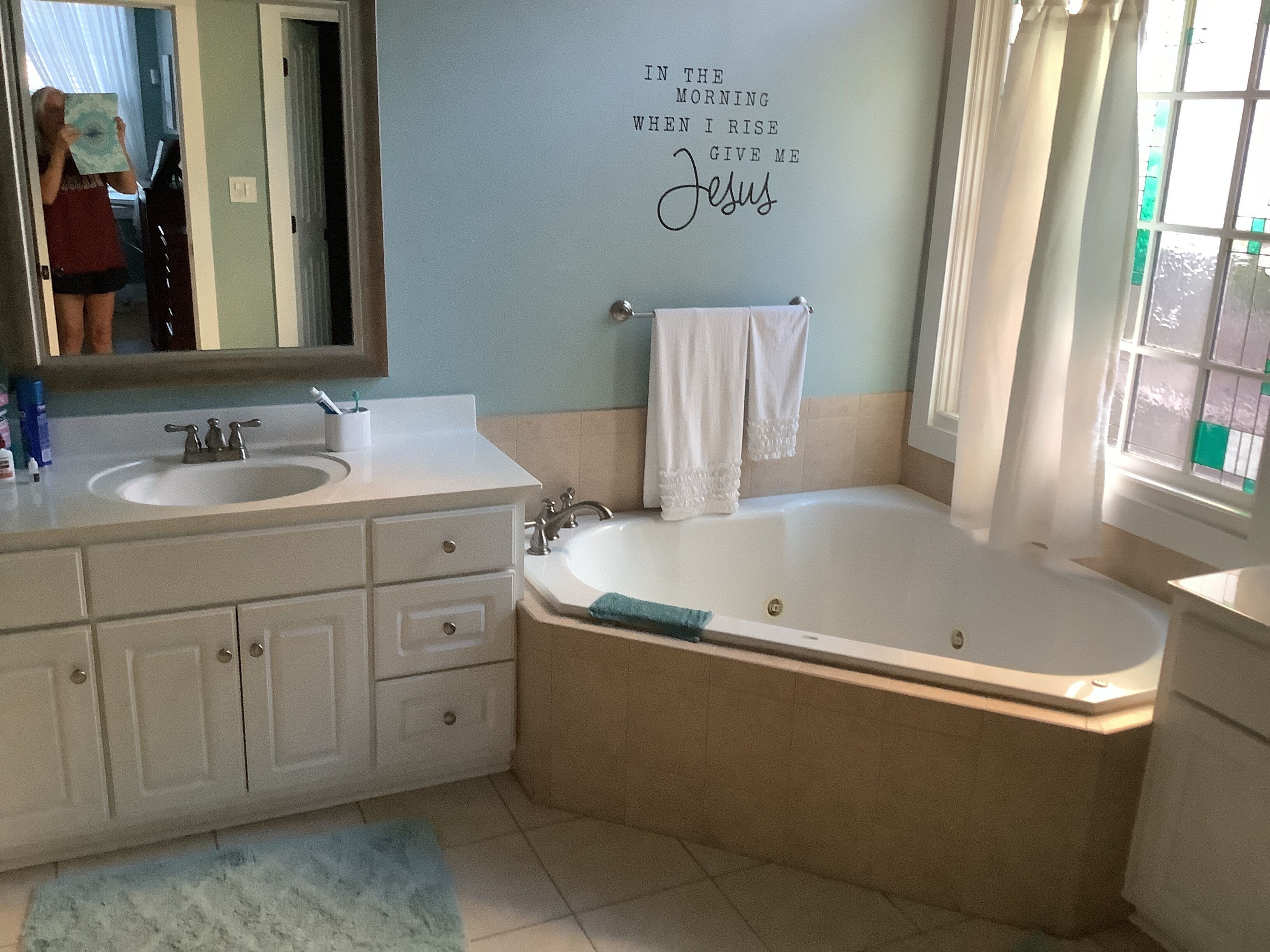 A bathroom with a double sink vanity, a bathtub, and a mirror.