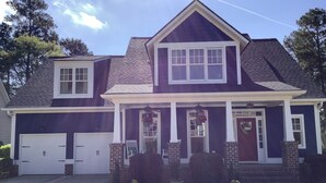 A two-story house with a front porch, a garage, and a well-maintained lawn.