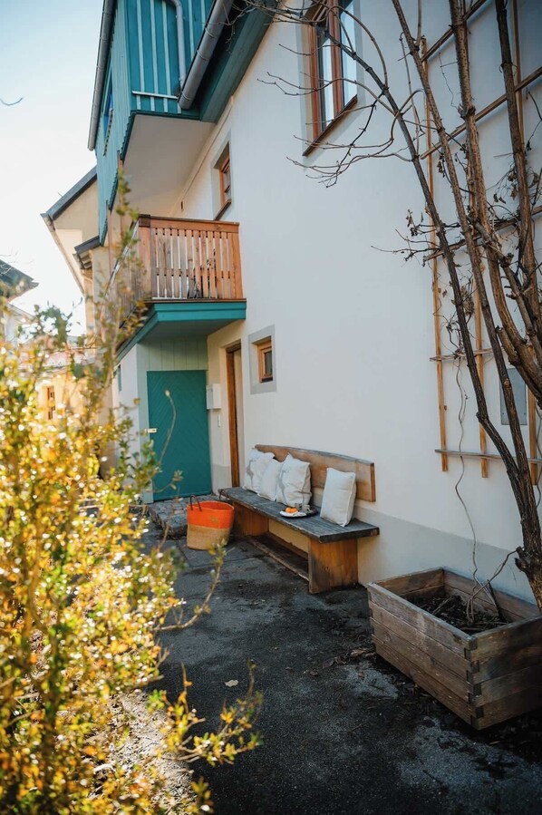 A courtyard with a wooden bench, a planter, and a green door. - Historic Cottage in Old Town - for 6 guests (Bad Tölz)
