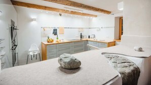 A modern kitchen with wooden beams, a sink, and a countertop with fruits and a bottle.