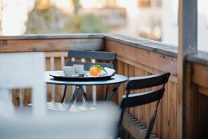 A small round table with a white plate, a cup, and a slice of orange on a balcony with wooden railings. - Historic Cottage in Old Town - for 6 guests (Bad Tölz)
