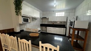 A kitchen with white cabinets, a black countertop, and wooden chairs.