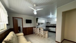 A living room with a sofa, dining table, chairs, and a ceiling fan.