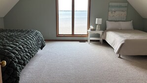 Quarto com uma janela grande, uma cama, uma mesa de cabeceira e um abajur.