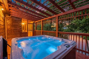 Een hottub onder een houten pergola met uitzicht op een meer.