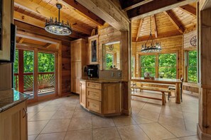 Interior de una cabaña de madera con cocina, comedor y ventanas amplias.