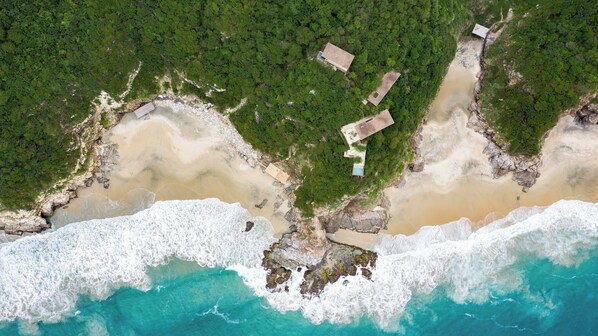 An aerial view of a coastal property with a beach, rocky shoreline, and dense greenery. - La Valise Mazunte, Member of Small Luxury Hotels (Santa María Tonameca)