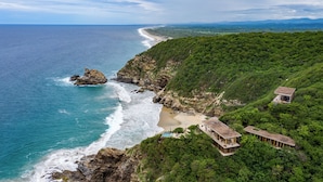 A coastal property with a beach, cliffside, and a house with a balcony overlooking the ocean. - La Valise Mazunte, Member of Small Luxury Hotels (Santa María Tonameca)