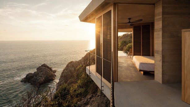 A modern bedroom with a large window overlooking the ocean, a ceiling fan, and a bed with a wooden headboard. - La Valise Mazunte, Member of Small Luxury Hotels (Santa María Tonameca)