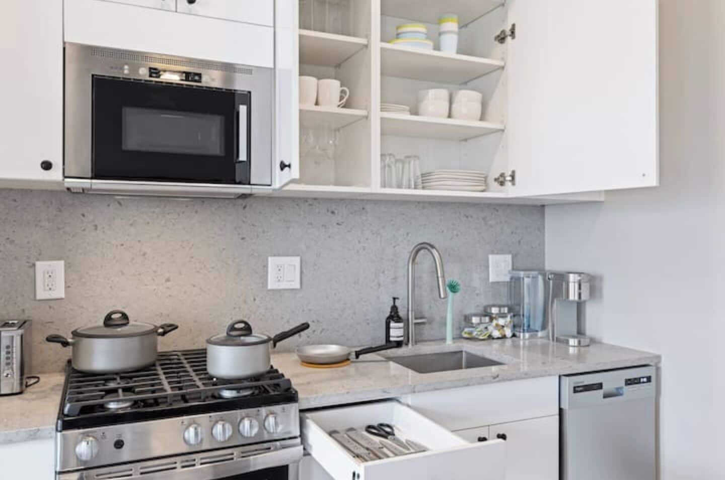A modern kitchen with a built-in microwave, stove, and sink.