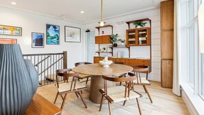 A dining area with a round wooden table, six chairs, a central light fixture, and a staircase with a railing. - Cozy 1-bedroom condo, fitness room in brilliant Atlanta-Ponce City Market Area (Atlanta)