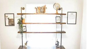 A desk with a wooden top, a chair, and a floating shelf with books and a globe.