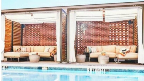A poolside area with two beige sofas and a brick wall backdrop.